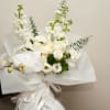 White bouquet with orchids, roses, and tall white blooms wrapped in paper