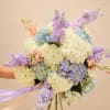 Creamy white hydrangeas take center stage in this large hand-tied bouquet, their