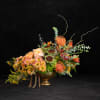 Orange and peach floral arrangement in a gold pedestal vase