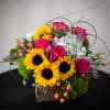 Bright bouquet with sunflowers, pink roses, and blue hydrangeas in a wooden box