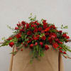 Large red rose arrangement with mixed greenery on a draped stand