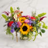 Colorful mixed bouquet in a clear glass vase with sunflowers and roses