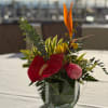 Tropical flower arrangement in a clear glass vase with red and pink blooms