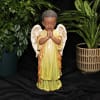 Angel figurine with potted plants on a black backdrop