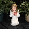 Angel figurine holding a red heart, surrounded by potted plants