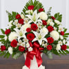 Large red, white, and green floral arrangement with lilies and roses in a white vase