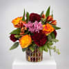 Colorful bouquet of roses, carnations, and chrysanthemums in a mosaic glass vase