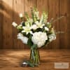 White lilies and hydrangeas in a clear glass vase