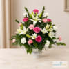 Pink roses and white lilies arranged in a white vase