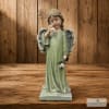 Angel figurine in a green robe holding a flower on a wooden background