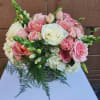 Round arrangement of pink and white roses with hydrangeas in a clear glass vase
