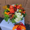 Hand-tied bouquet of orange roses and white hydrangeas with mini pumpkin accents and ivy, tied with an orange ribbon.