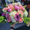 Low round arrangement of pink roses, lisianthus, and white hydrangeas in a clear glass bowl.