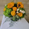 Round arrangement of yellow sunflowers and roses with green hydrangeas and cream spray roses.