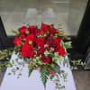 Low arrangement of red roses with trailing greenery in a red container
