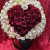 Heart-shaped bouquet of red and pale pink roses in a black box with a red ribbon