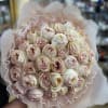 Bouquet of pale pink and cream roses wrapped in lace-like paper