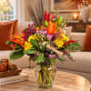 Colorful autumn bouquet in a clear glass vase on a coffee table