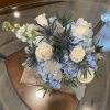 Bouquet of white roses and blue hydrangeas with spiky thistle flowers
