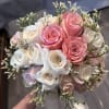Handheld bouquet of pink and white roses with small filler flowers