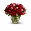 Red roses and pink tulips arranged in a clear glass vase
