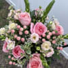 Pink roses and mixed blooms arranged in a hand-tied bouquet