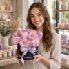 Woman holding a pink and lavender flower box with a ribbon