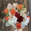 Bouquet of coral and blush roses with white blooms on a rustic wood surface