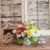 Basket arrangement of yellow and orange roses with white and purple daisies
