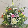 Large mixed flower arrangement in a woven basket with white, pink, and orange blooms