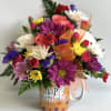 Colorful mixed flower bouquet in a birthday mug with orange ribbon