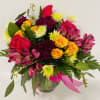 Mixed bouquet of roses and daisies in a glass vase with pink ribbon