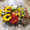 Mixed bouquet with sunflowers, roses, orchids, and tulips on a wooden floor