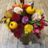 Mixed bouquet with roses, tulips, and small pumpkins in a glass vase