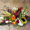Colorful floral arrangement in a wicker cone basket with sunflowers and roses