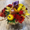 Colorful floral arrangement with roses, calla lilies, and orchids in a gold vase
