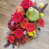 Red roses arranged with decorative fruit accents on a wooden surface