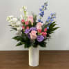 Mixed pink, purple, white, and blue flowers in a white vase