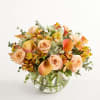 Peach roses and orange calla lilies in a clear glass vase