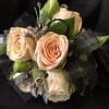 Peach roses arranged with black ribbon on a dark background