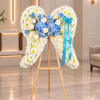 Heart-shaped floral wreath on a wooden easel with blue ribbon
