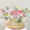 Pastel bouquet of roses and daisies in a white container