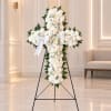 White floral cross on a black stand with a ribbon bow