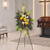 Standing floral spray with yellow, white, and purple flowers on an easel