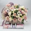 Large pastel rose arrangement with candles and gift boxes in a clear tray