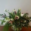 Low glass vase arrangement with white and purple calla lilies, white blooms, and abundant greenery.