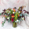 Mixed floral arrangement in a glass vase with orange calla lilies and white pom flowers