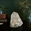 Crystal geode on a dark surface with glass vases and greenery