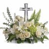 Low arrangement of white lilies and roses with green hydrangea and a clear crystal cross in the center