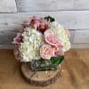 This clear cube with white hydrangeas, pink roses and cybidium orchids is